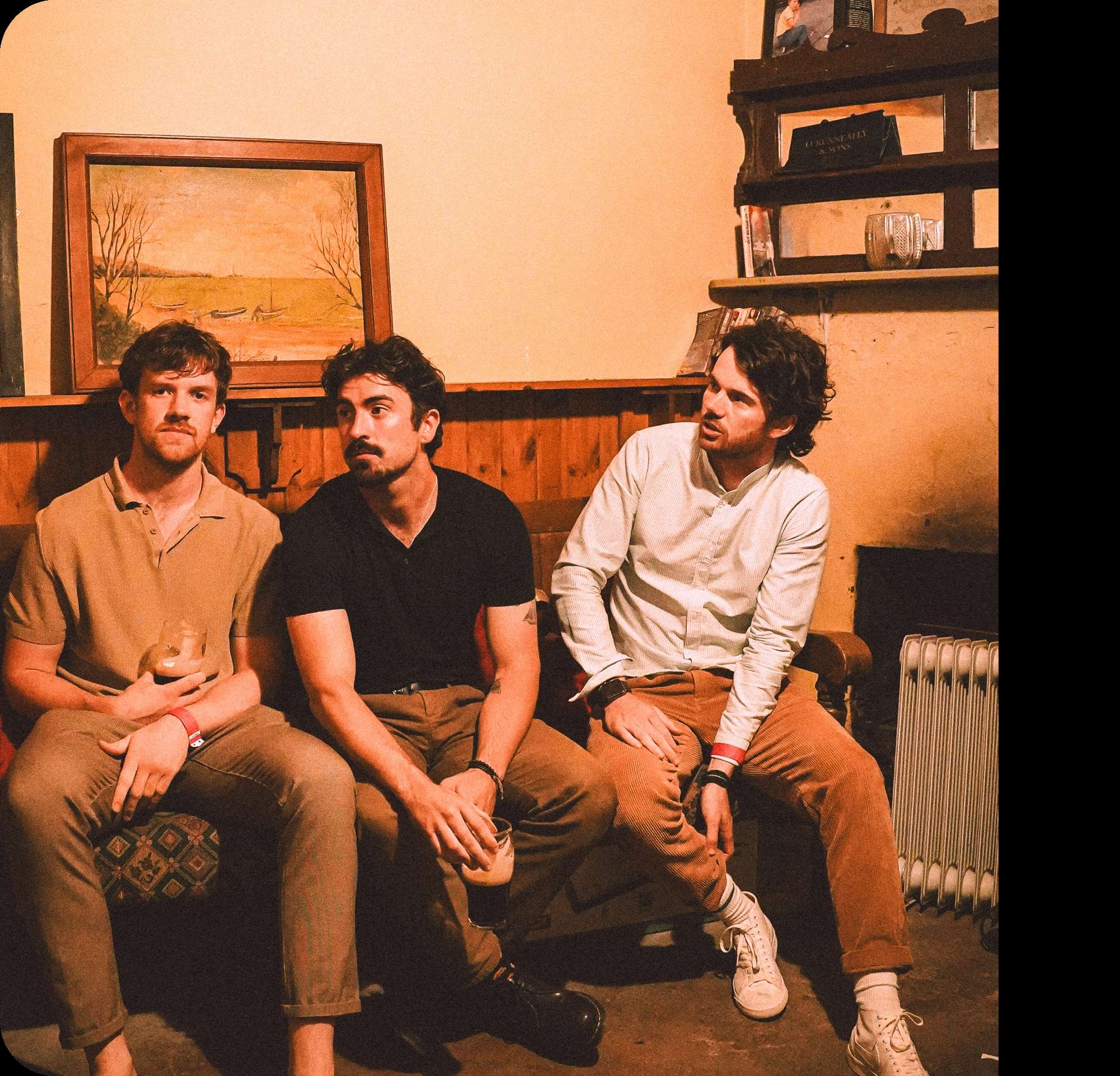 The members of Amble sitting in a cozy, dimly lit room with wooden paneling.